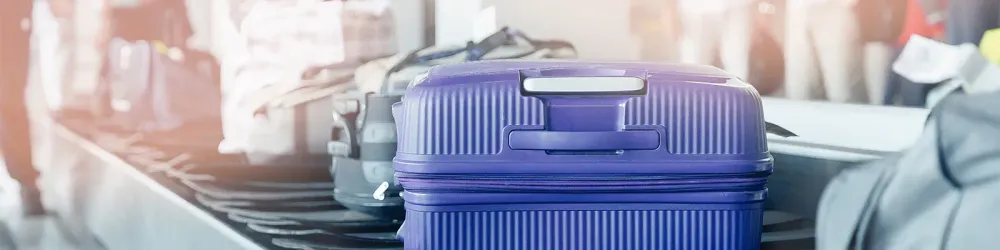 Hardside blue suitcase coming down the conveyor belt at baggage claim